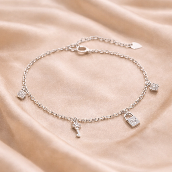 Silver bracelet with charms on a beige fabric background