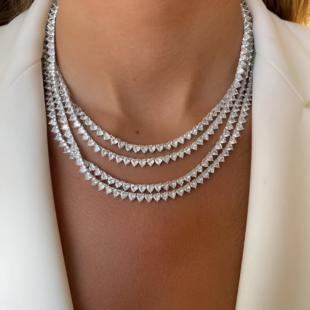 Close-up of a person wearing a sparkling diamond necklace on a plain background