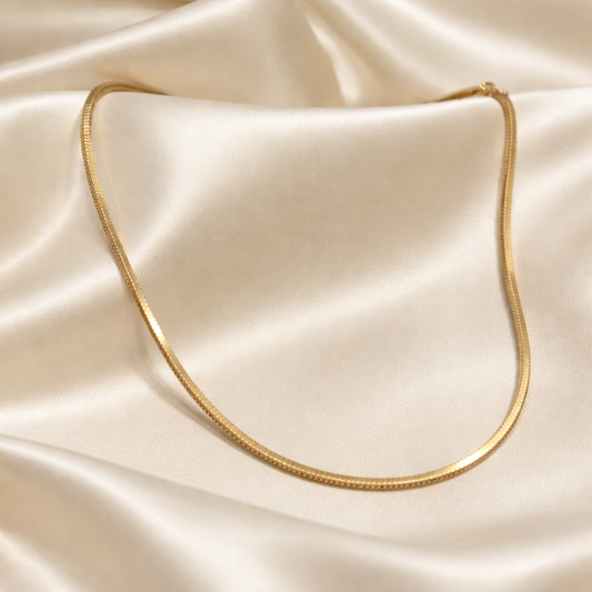 Gold necklace on a beige satin fabric