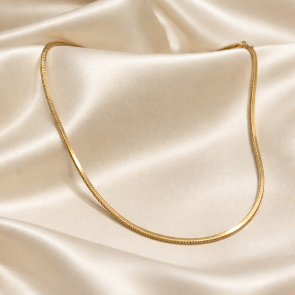 Gold necklace on a beige satin fabric
