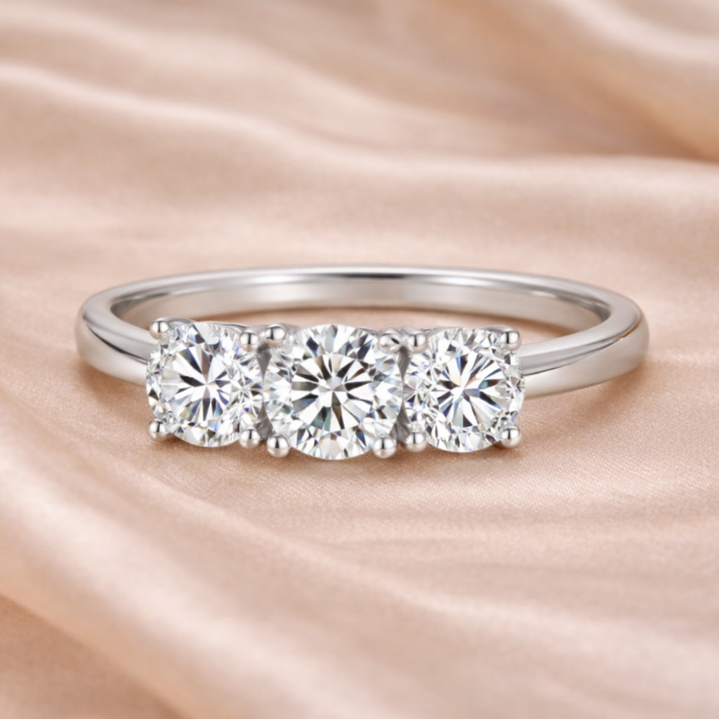 Silver ring with three diamonds on a soft pink fabric background