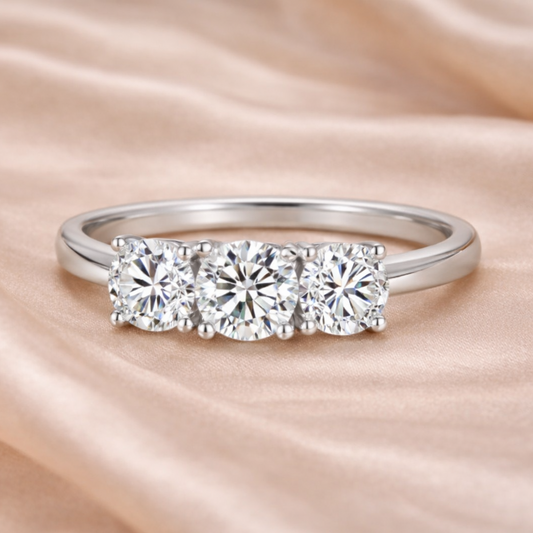 Silver ring with three diamonds on a soft pink fabric background