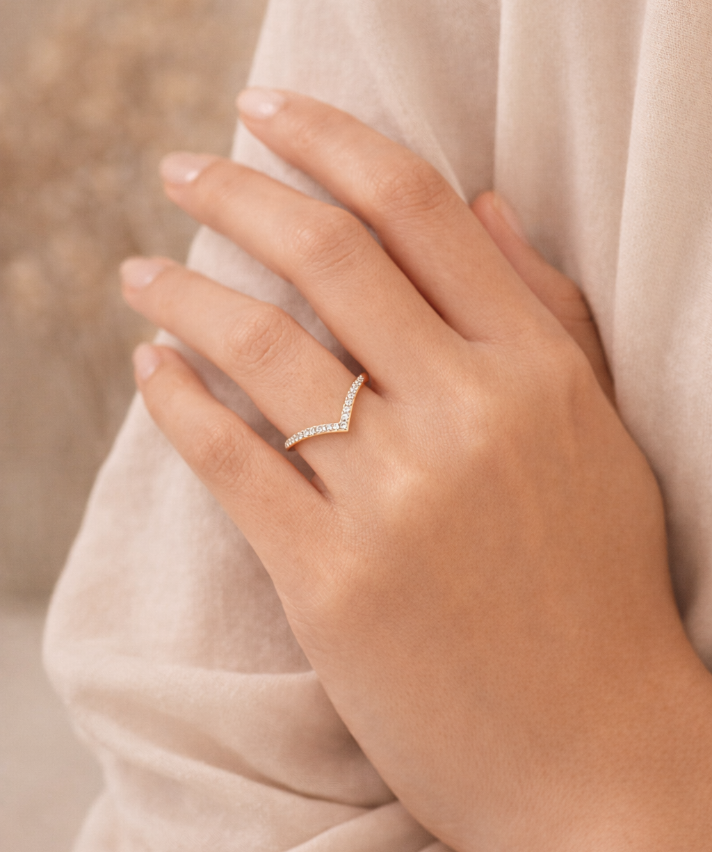 Hand wearing a diamond ring with a soft beige background
