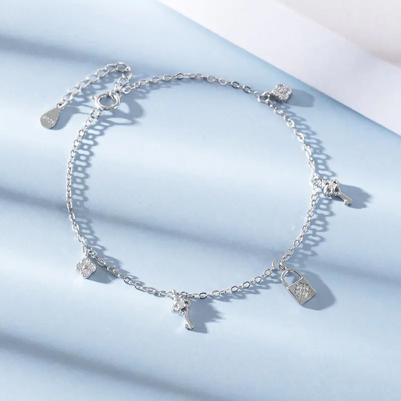 Silver anklet with charms on a light blue background