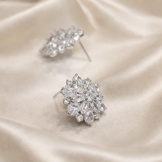 Pair of silver floral earrings on a satin surface