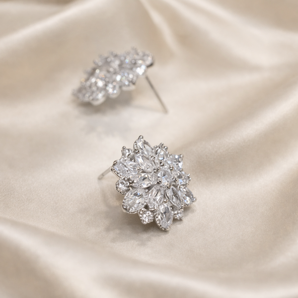 Pair of silver floral earrings on a satin surface