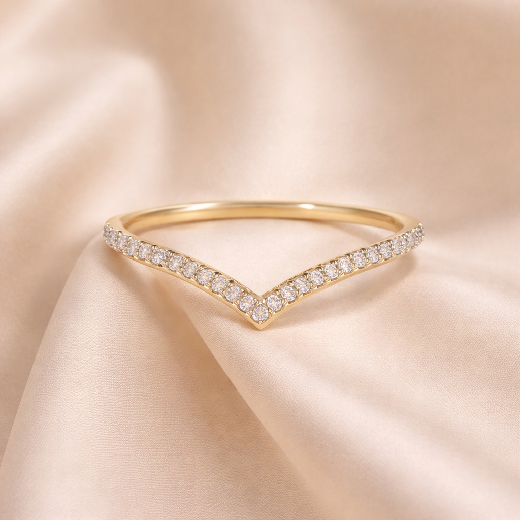 Gold ring with diamond accents on a beige satin background