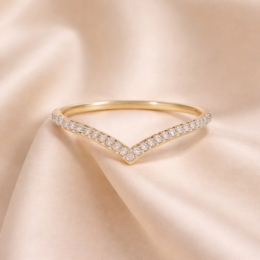 Gold ring with diamond accents on a beige satin background