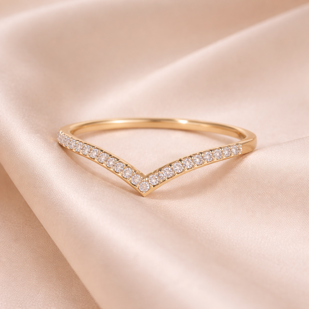 Gold ring with diamond accents on a soft pink fabric background