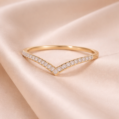 Gold ring with diamond accents on a soft pink fabric background