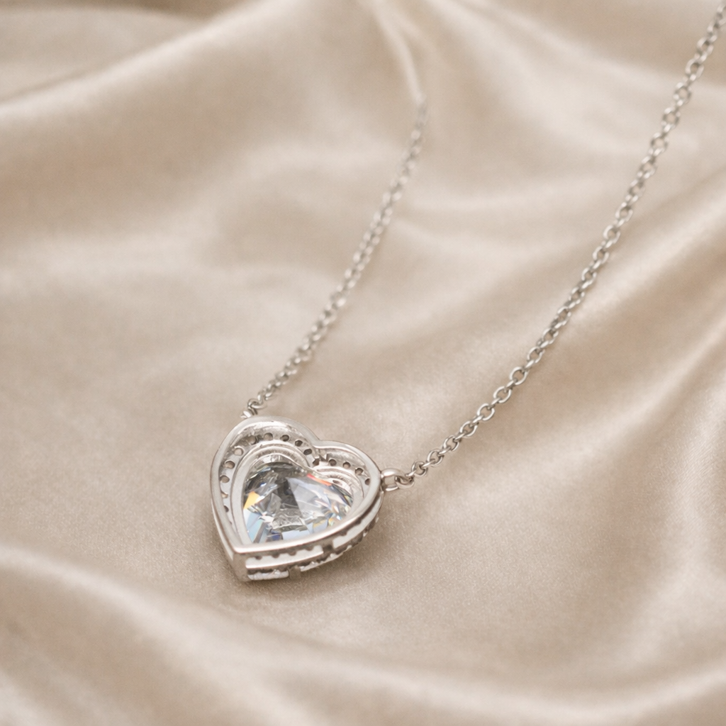 Heart-shaped silver pendant necklace on a beige satin background