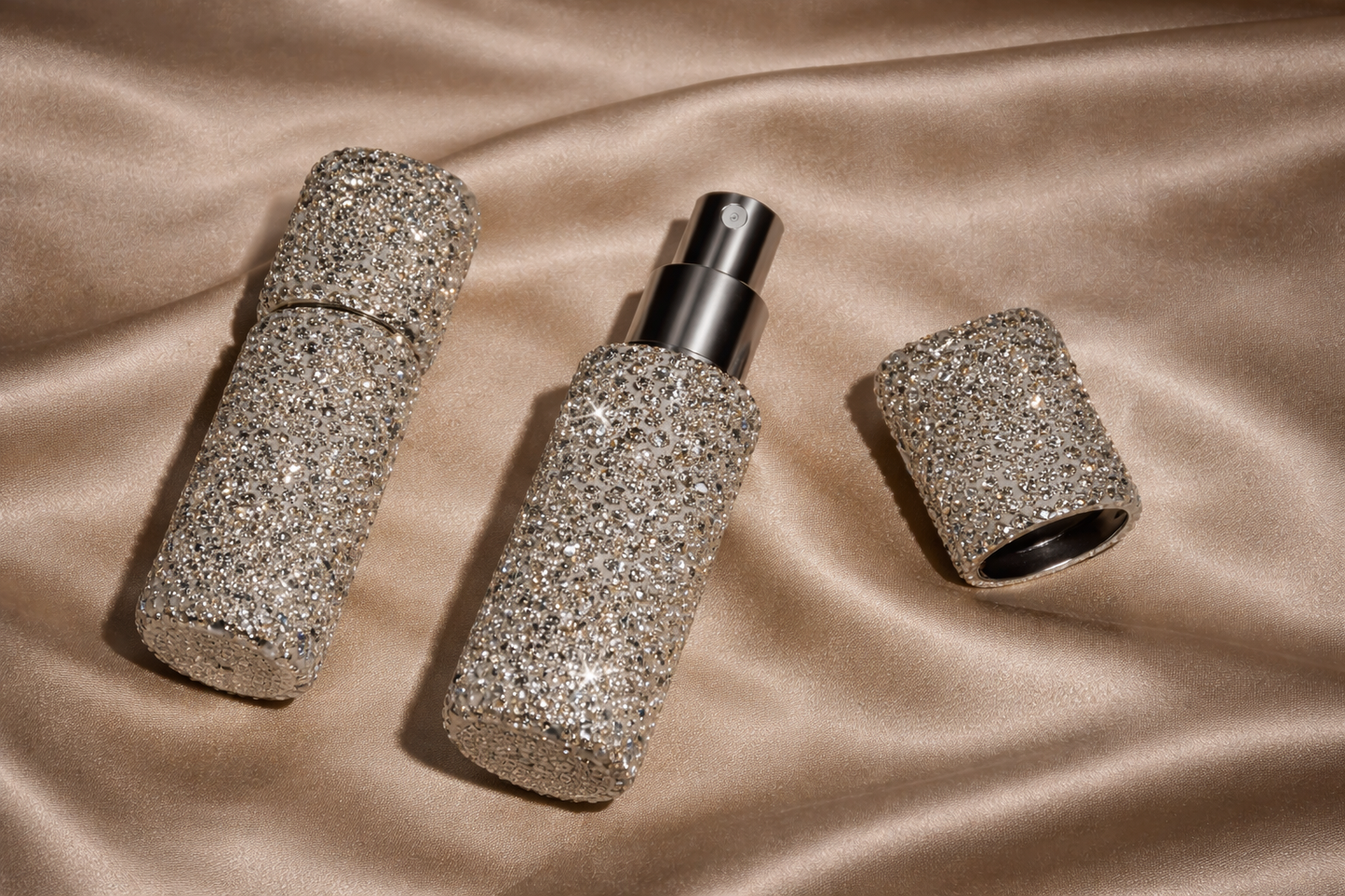Three glittery perfume bottles on a satin surface