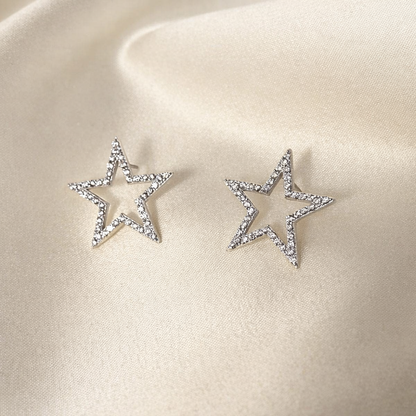 Star-shaped earrings with sparkling details on a beige satin background